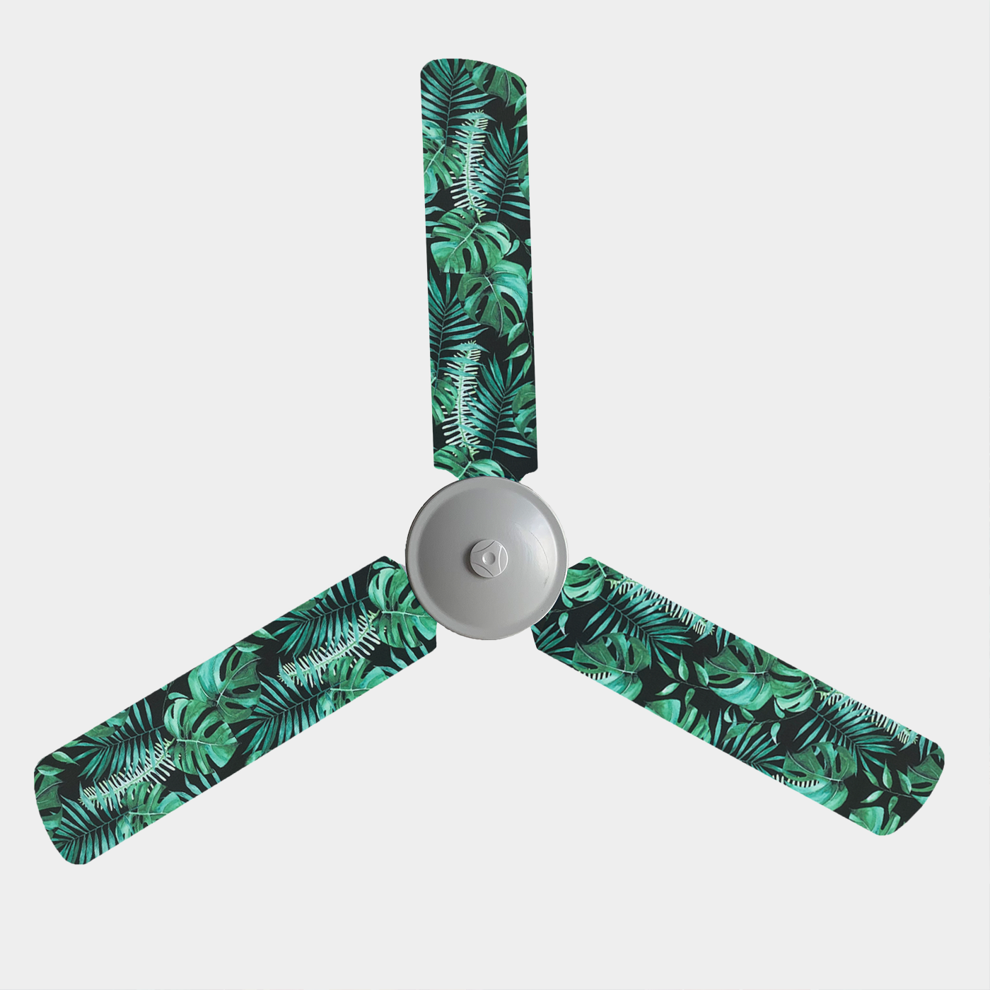 Three blade ceiling fan with fan covers with black background and large green leaves and ferns